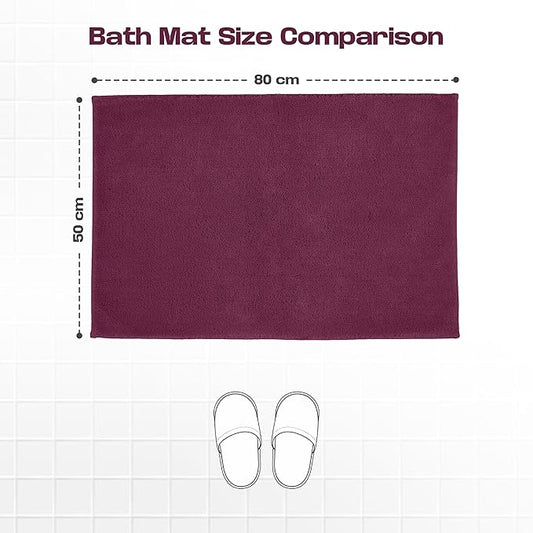 Plum bath mat 50x80 cm displayed on white tile floor with slippers and size comparison chart.