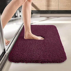Plush maroon bathmat in bathroom with foot stepping out of shower onto soft surface