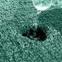 Water being poured onto an absorbent, textured bathmat surface