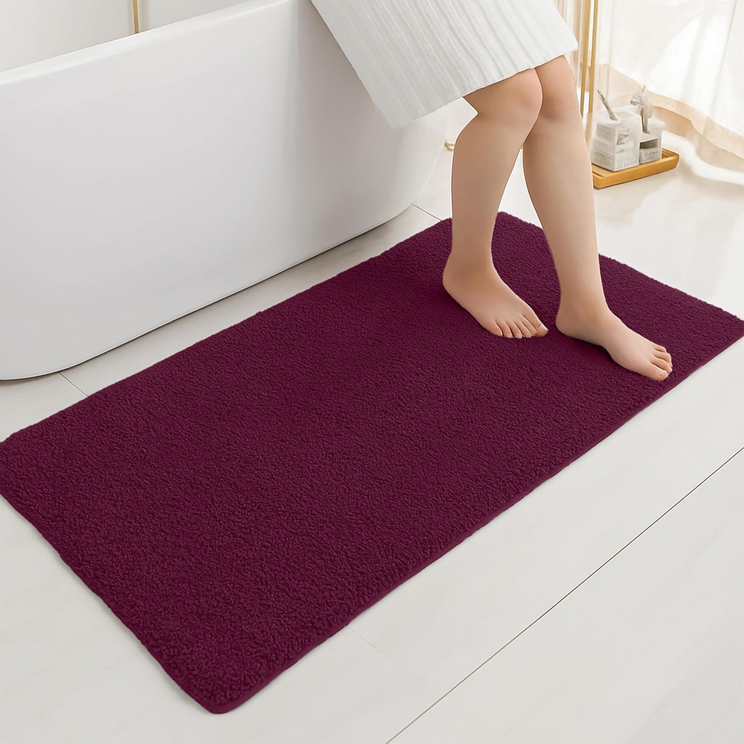 Plush burgundy bathmat in a modern bathroom setting with a person stepping out of the tub