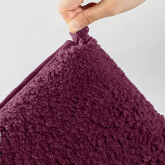 Hand holding a soft, textured maroon pillow for bedroom decor