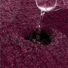 Water being poured on a dark purple absorbent bathmat showing high absorbency.