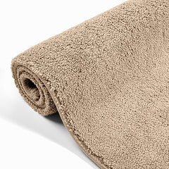 Beige rolled terry bathmat with soft, textured surface on a white background