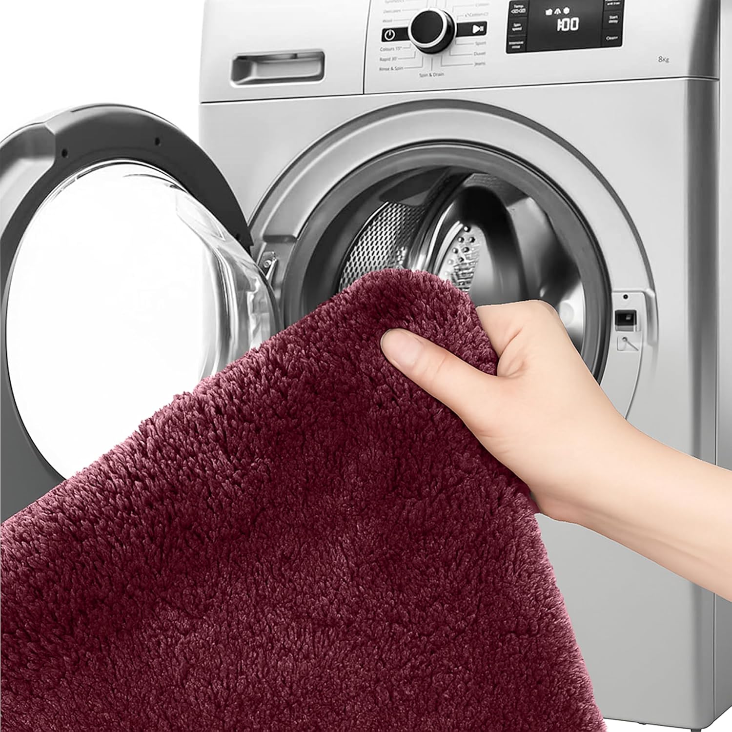 Hand holding a plush maroon bathmat in front of a washing machine