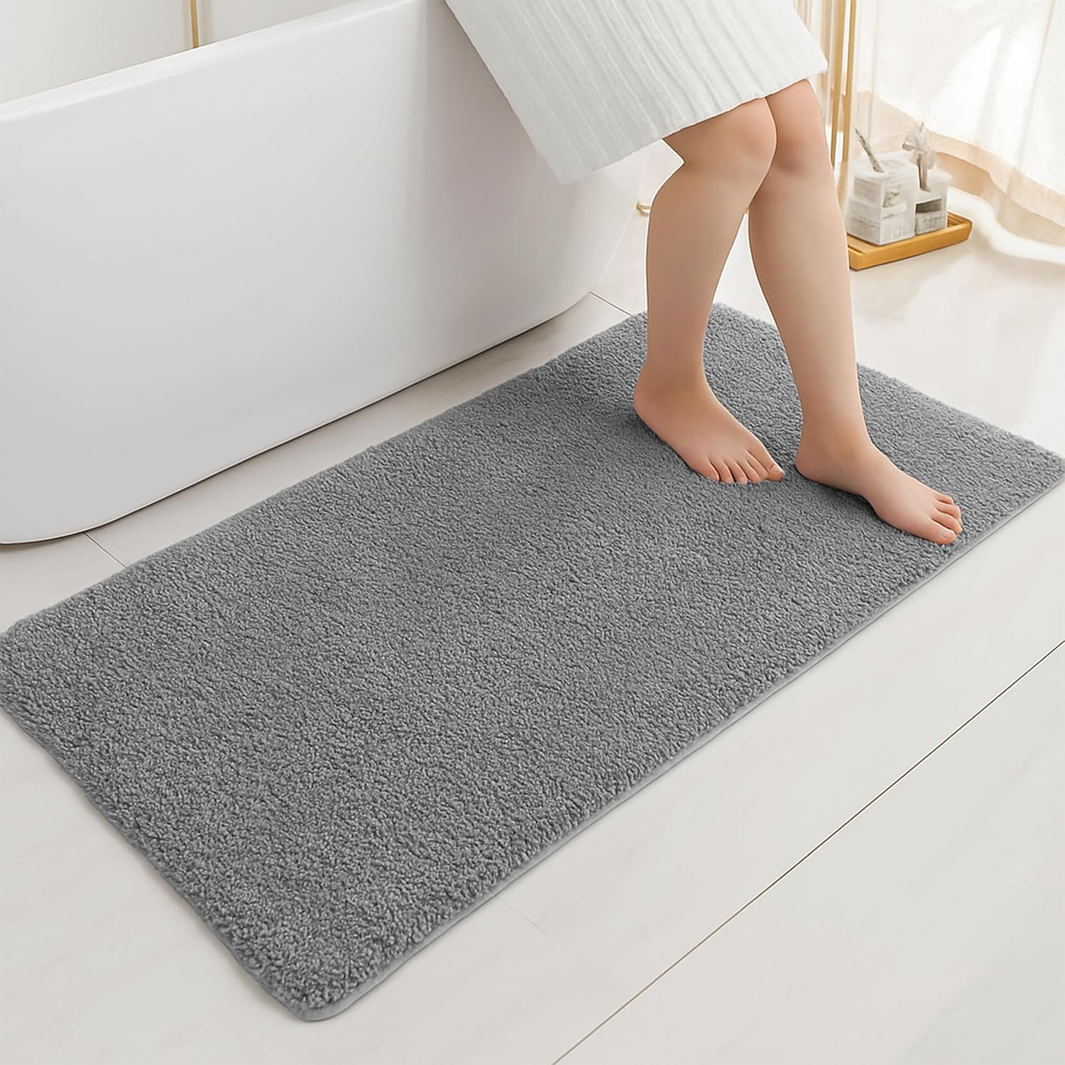 Soft grey bathmat in bathroom setting with bare feet stepping out of a tub