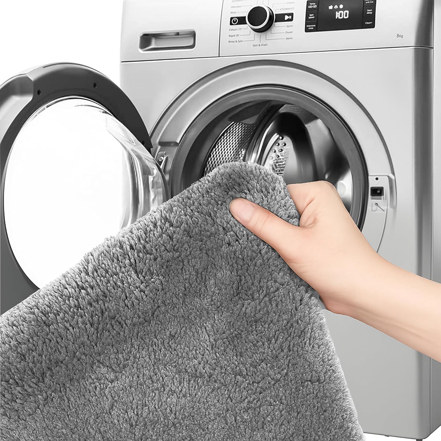 Hand holding a soft grey bathmat near a washing machine, showing washable home textile