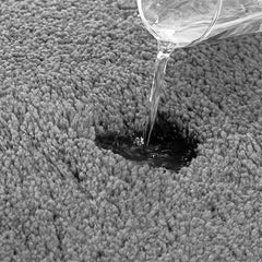 Water being poured on a grey absorbent bathmat to show quick-dry feature