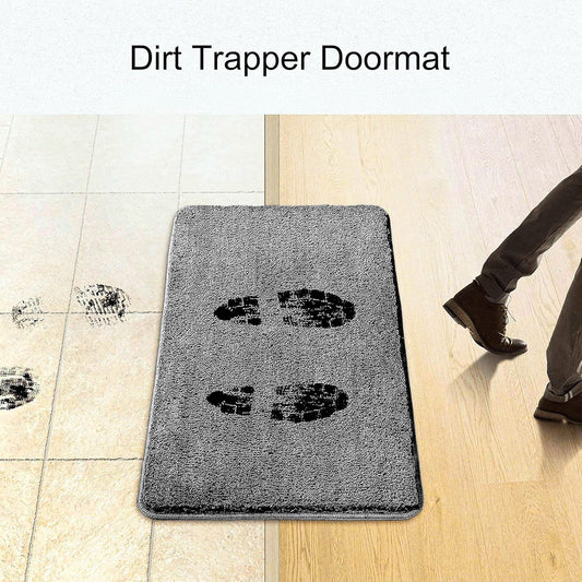 Grey dirt trapper doormat with black shoe prints on tile and wooden floor entryway.