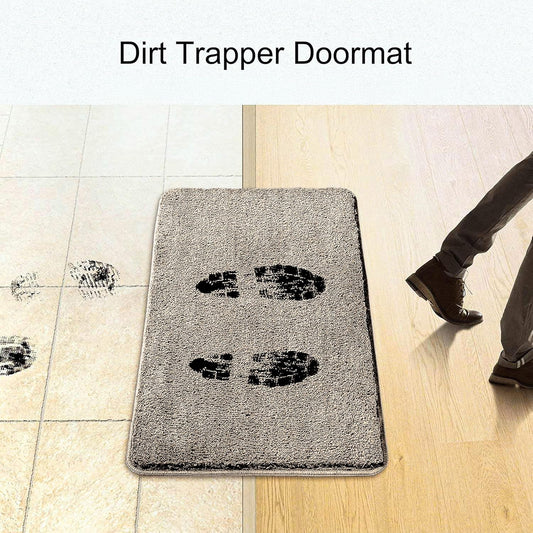 Gray dirt trapper doormat with black footprints, placed between tile and wooden floor, person walking on it