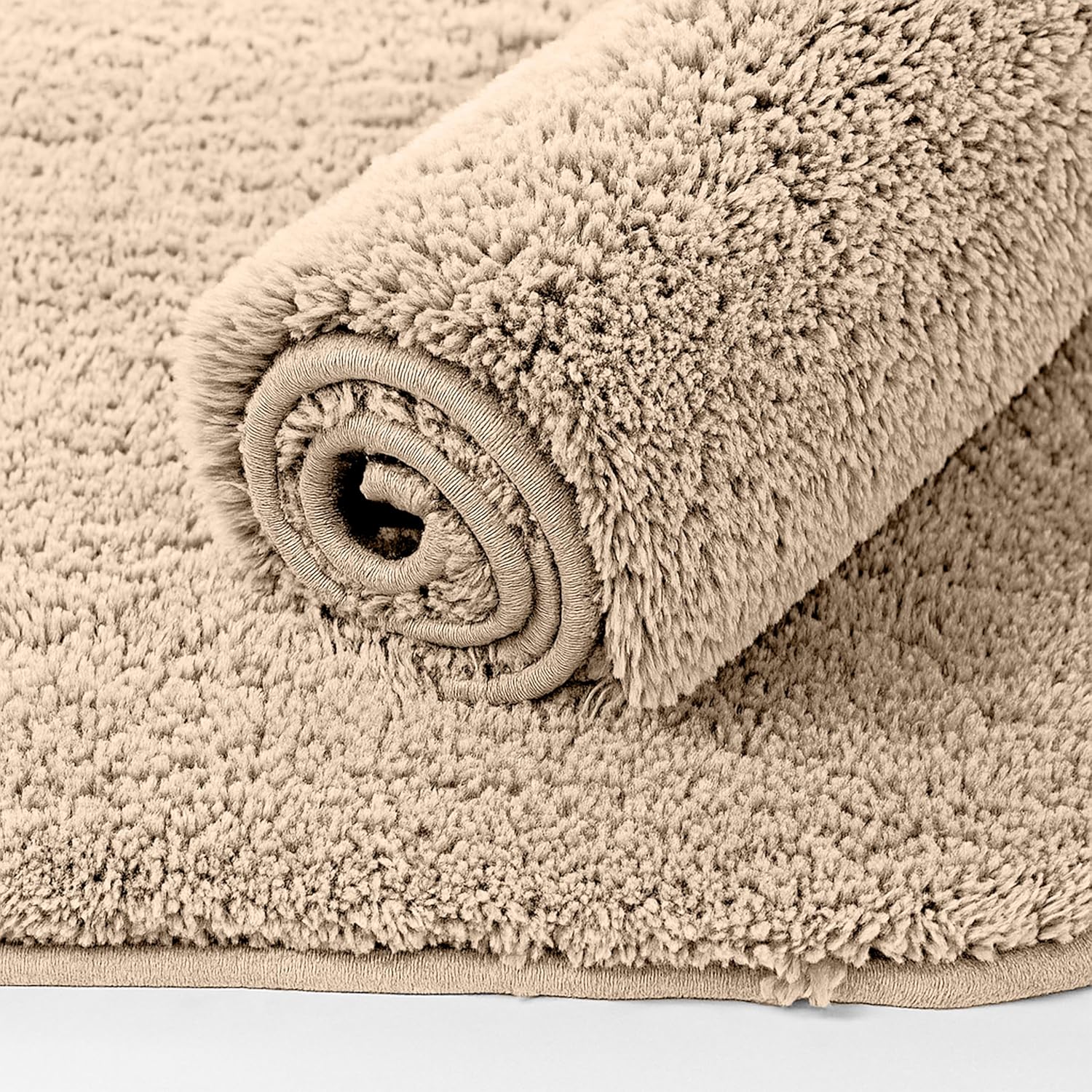 Beige plush bathmat rolled up, soft textured bathroom floor mat