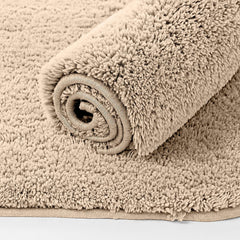Beige plush bathmat rolled up, soft textured bathroom floor mat