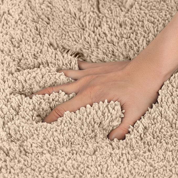 Hand pressing into soft beige bathmat with plush, textured surface